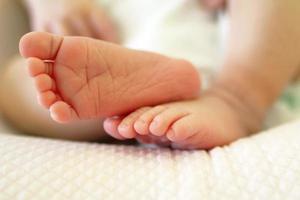 Tiny delicate feet of newborn baby on a bed. photo