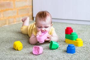 Candid lifestyle portrait of little girl. Toddler child playing with soft plastic colorful constructor. photo