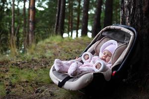 Cute three month child in car seat near a tree in a forest. photo