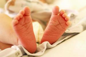 Tiny delicate feet of newborn baby on a bed. photo