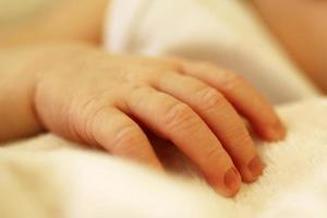 Tiny delicate hand of newborn on beige blanket. photo