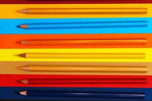 Colored pencils on a multi-colored background. Many pencils of different colors. photo