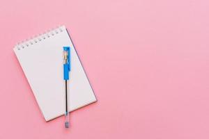 Open spiral notepad on pink background, notepad and blue pen lie on paper, flat photo