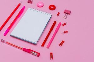 Markers of different pink shades with white notepad on pink background, top photo