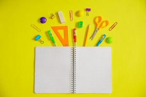 Notebook on a spring for notes and stationery lie on a yellow background photo