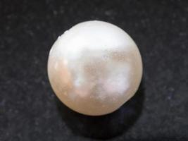 bead from white Pearl gemstone on dark photo