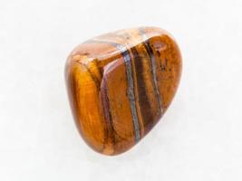 tumbled tigers eye gemstone on white marble photo