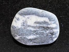 pebble of gray Gneiss stone on dark photo