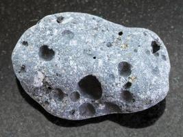 pebble of gray pumice stone on dark background photo