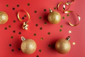 composición plana con serpentinas doradas y adornos navideños sobre fondo rojo foto
