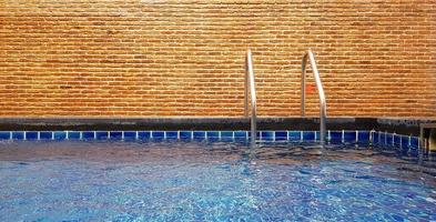 piscina con escalera y fondo de pared de ladrillo con espacio para copiar. interiorismo y estructura. foto
