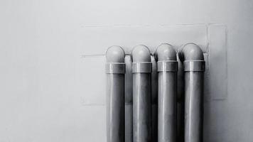 cuatro tuberías de agua en una pared de hormigón para fondo con espacio de copia en tono blanco y negro. tubería de aceite instalada en el suelo en estilo monocromo. foto