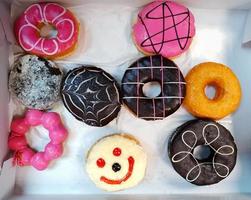 Top view of colorful donut on white paper background. Flat lay of dessert contains in box. Food design and unhealthy or junk food concept. photo