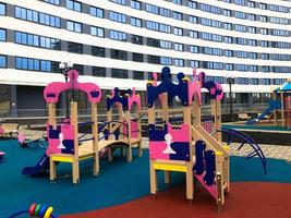 children's pink playground in the center of the residential complex. there are swings, fitness equipment, fun slides and climbing frames for kids. playground in a new area next to tall photo