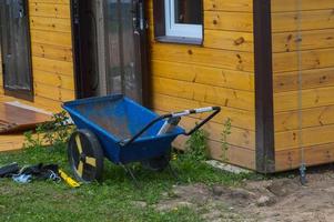 carro industrial de construcción de dos ruedas, silla de ruedas, puestos de herramientas en la calle cerca de la casa de un garaje en un sitio de construcción foto