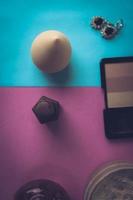 Beauty box, makeup kit, powder and blush with beauty blender, perfume, lipstick, highlighter and earrings for makeup on a pink purple and blue background. Flat lay. Top view photo