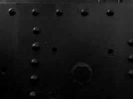 Black iron metal rough painted strong solid industrial wall with rivet holes and bolts. Background, texture photo