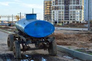 estación móvil de suministro de agua en el centro de la ciudad. un gran auto azul sobre ruedas con un tanque lleno de agua la entrega a las personas en botellas y contenedores. falta de agua, sed, pobreza de la población foto