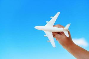 un avión de juguete blanco en la mano de un niño contra un cielo azul. foto