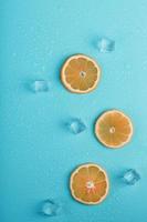 Slices of fresh orange on a blue background with ice. photo