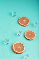 Slices of fresh orange on a blue background with ice. photo