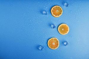 Slices of fresh orange on a blue background with ice. photo