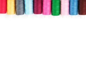 Sewing threads of different colors on reels on a white background. Free space, close-up. Isolate photo