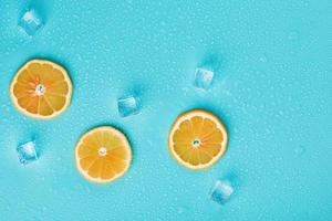 Slices of fresh orange on a blue background with ice. photo