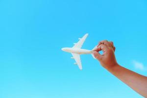 A white toy plane in a child's hand against a blue sky. photo