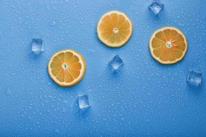 Slices of fresh orange on a blue background with ice. photo