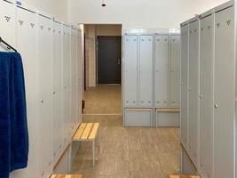 Metal lockers for clothes and benches in the locker room in the gym or at work at the enterprise for changing clothes for visitors or workers photo