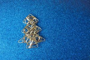 Festive New Year Christmas happy blue shiny joyful background with a small toy metal iron silver homemade Christmas tree. Flat lay. Top view. Holiday decorations photo