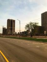 city panorama. tall glass houses stand along an asphalt road with a yellow stripe. near lampposts to illuminate the road and green trees with crowns. panoramic glazing of buildings photo
