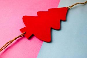 Festive New Year's Christmas beautiful bright multi-colored joyful blue and pink background with a small toy wooden red and white cute Christmas tree. Flat lay. Top view. Holiday decorations photo