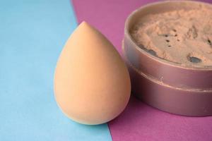 Beauty box, set of female cosmetics, crumbly matte mineral powder and blush with a beauty blender for makeup on a blue pink and purple background. Flat lay. Top view photo