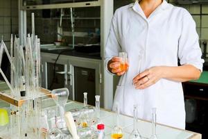 A female laboratory assistant, a doctor, a chemist, works with flasks, test tubes, makes solutions, medicines, mixes the ingredients in the laboratory. Laboratory assistant carries out the research photo