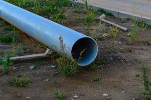 a large gray metal pipe with a hole lies on the wet ground in the city. construction site, water drainage system. sewerage production. water drains underground photo