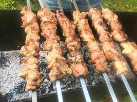 Beautiful tasty, appetizing meat, grilled kebabs on coals and natural smoke on the grill with roasted smoked crust on skewers. Concept camping, picnic, barbecue, grill photo