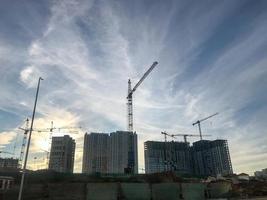 urban landscape, construction of a new district in the city. construction cranes, concrete block houses. construction of a multifunctional complex. sunny and clear day photo