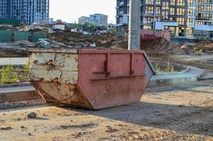 a large, rusty and pink dumpster for construction waste. a container for collecting garbage during the construction of a large residential complex in the city center. collection of bulky cargo photo