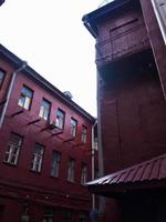 edificios rojos, un acogedor patio para salir y pasar tiempo en un café. las casas se colocan en las esquinas entre sí. junto a ella se encuentra el tejado de pizarra roja de una de las casas. lindos patios de la ciudad foto