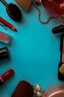 Frame from a set of female cosmetics from a lipstick, a highlighter, a pencil for lips, brushes, brushes, perfume, powder, ornaments on a blue background. Beauty box Flat lay. Top view photo