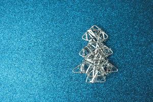 Festive New Year Christmas happy blue shiny joyful background with a small toy metal iron silver homemade Christmas tree. Flat lay. Top view. Holiday decorations photo