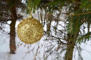 Beautiful festive elegant yellow, golden round balls, Christmas decorations for the new year, Christmas hanging on fir branches against the background of white snow in winter photo