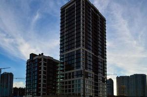 residential block of flats, tall brown and white. houses of different heights in the city center. made of glass and concrete for human life. against the blue-white sky photo