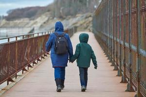 vista trasera de madre e hijo caminando cerca del mar de invierno foto