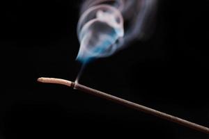 Smoke curls from burning incense stick for relaxation and meditation black background photo