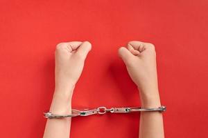 Hands in handcuffs on red background. photo