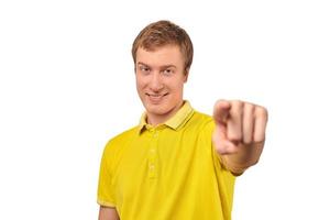 Smiling attractive handsome guy in casual yellow T-shirt pointing forward, isolated white background photo