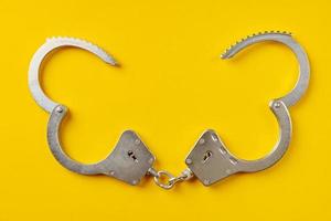 Opened handcuffs on yellow background. photo